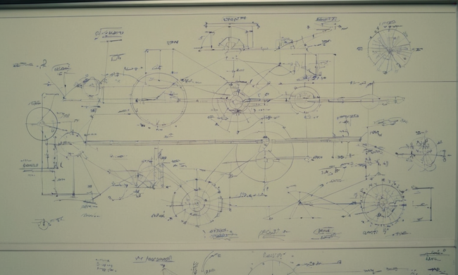 Gráficos y fórmulas en una pizarra rodeada de engranajes mecánicos y diagramas.